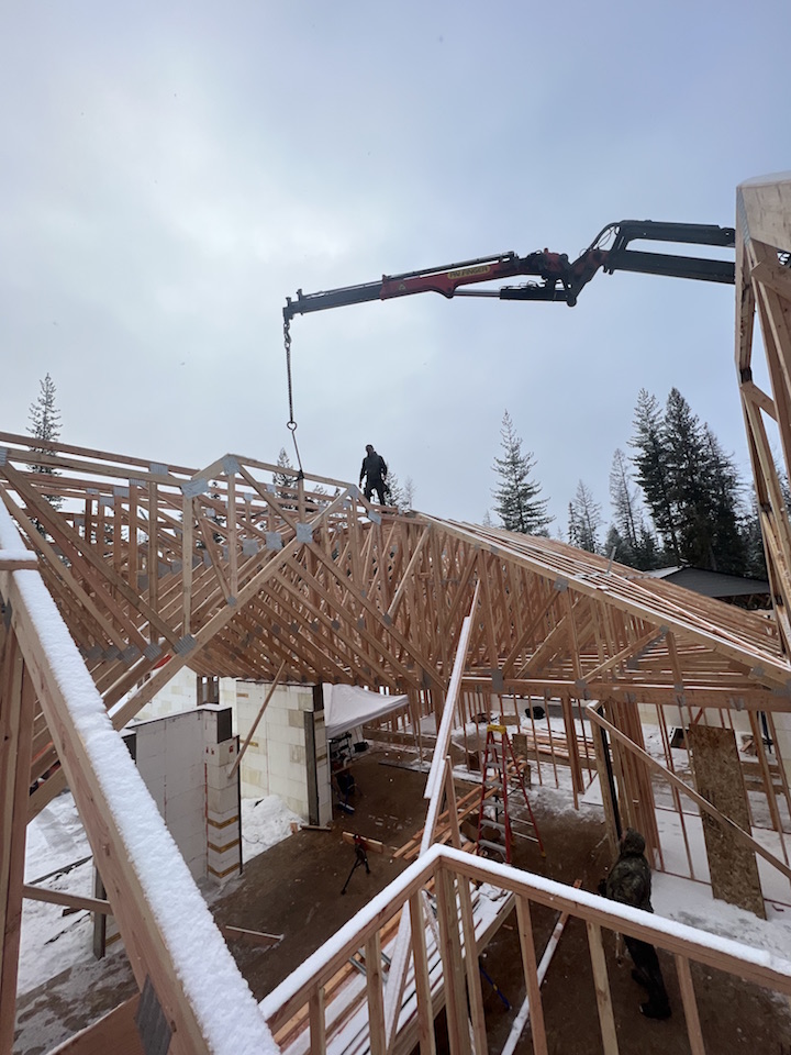 Chris Turnbull of Box H Construction setting trusses on massive new home in Sandpoint Idaho